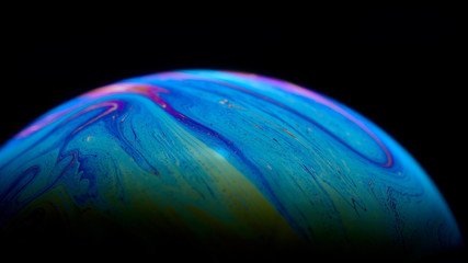 Psychedelic abstract planet-like soap bubble, light refraction on a soap bubble, colors in soap bubble.