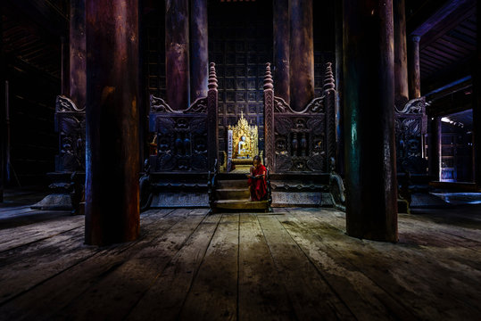 Monk siting by ornate shrine in temple
