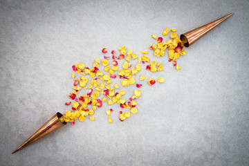 Copper cones with rose petals on concrete surface