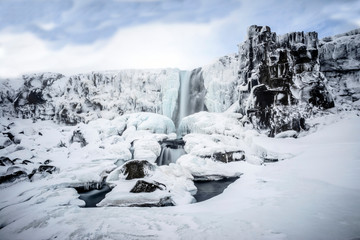 Waterfall pouring over icy cliffs in remote landscape