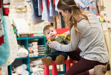 Caucasian mother and baby son shopping in clothing store
