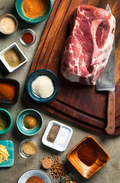 Overhead view of variety of spices and pork on table