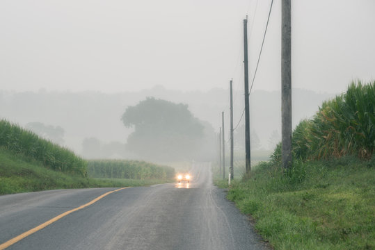 Car approaching on foggy two-lane road