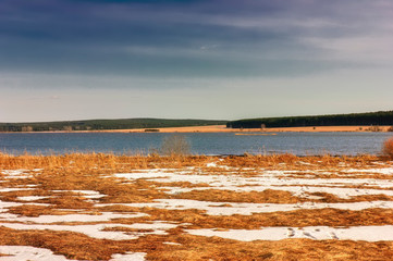 Early Spring landscape melts ice on a small river at the edge of the village.