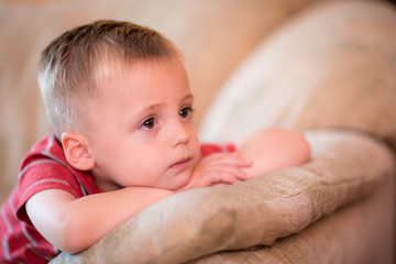Cute little boy sitting on a sofa and watching tv