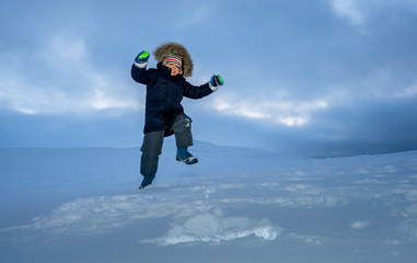 Fototapeta na wymiar Happy little boy jumping in the snow