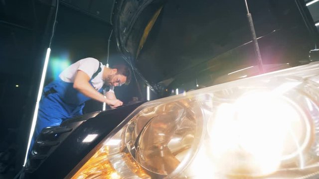 Switched on headlight of a car which is being fixed by a man