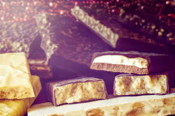 Turron. Warm sunlight. Selective focus. Blurred background. Traditional Spanish Christmas candy. Torrone and nougat with nuts. Texture, layers.