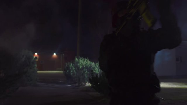 Masked Team of Armed SWAT Police Officers Run in Formation Outside at Night. Soldiers with Rifles and Flashlights Run on a Street Filled with Smoke.