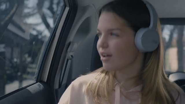 Girl singing and dancing in the car while wearing headphones