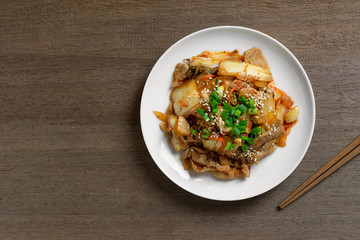 top view of stir fried pork with kimchi in a ceramic dish on wooden table. homemade style food concept.