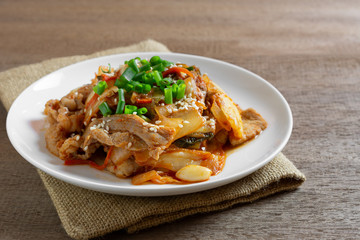 close up of stir fried pork with kimchi in a ceramic dish on wooden table. homemade style food concept.