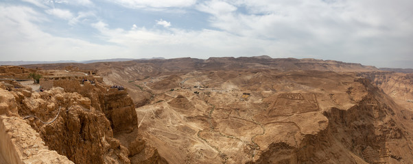 Beautiful panoramic view of an ancient fortress on top of a mountain during a cloudy and sunny day. Taken in Masada National Park, Israel.
