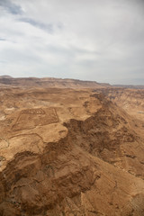 Fototapeta na wymiar Beautiful aerial view of a mountain desert landscape during a cloudy and sunny day. Taken in Masada National Park, Israel.