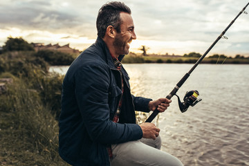 Man enjoying fishing near a lake - Powered by Adobe