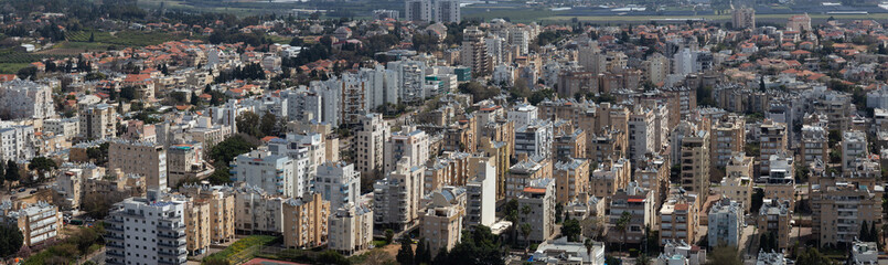 Fototapeta na wymiar Aerial panoramic view of a residential neighborhood in a city during a cloudy and sunny day. Taken in Netanya, Center District, Israel.