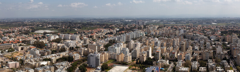 Fototapeta na wymiar Aerial panoramic view of a residential neighborhood in a city during a cloudy and sunny day. Taken in Netanya, Center District, Israel.