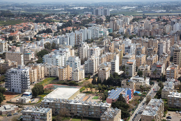 Aerial view of a residential neighborhood in a city during a cloudy and sunny day. Taken in Netanya, Center District, Israel.