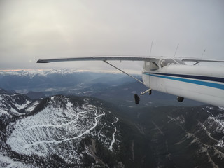Aerial view of a small airplane flying over the Canadian Mountain Landscape during a gloomy cloudy evening. Taken near Vancouver, British Columbia, Canada.