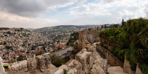 Fototapeta na wymiar Beautiful panoramic view of the Walls of Jerusalem surrounding the Old City with the cityscape in the background during a cloudy day. Taken near the Jerusalem, Israel.