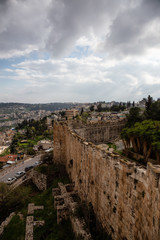 Beautiful view of the Walls of Jerusalem surrounding the Old City with the cityscape in the background during a cloudy day. Taken near the Jerusalem, Israel.