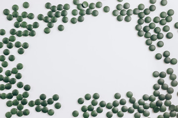 green spirulina pills on white background