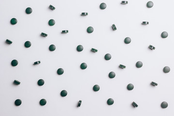 green spirulina pills on white background