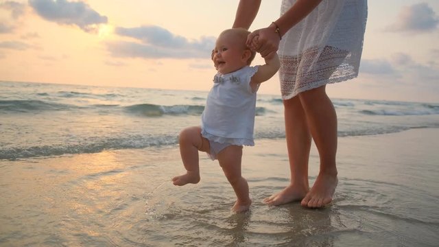 YounYoung Beautiful Woman Walks With Her Little baby On The Seashore At Sunsetg Beautiful Woman Walks With Her Little baby On The Seashore At Sunset. 4k