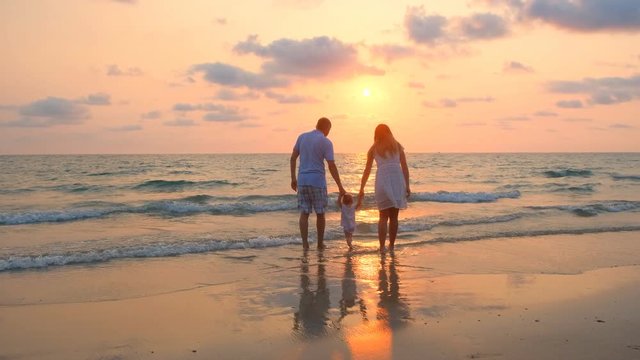 Happy family walking along the sea coast at sunset. 4k