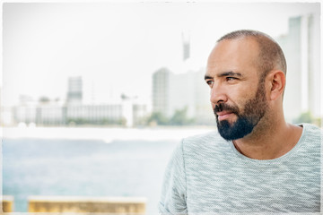 Portrait of a spanish man with beard and short buzz hair, looking away, casual, pensive, dreaming,...