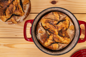 Traditional artisan bread with red baking pan, top view