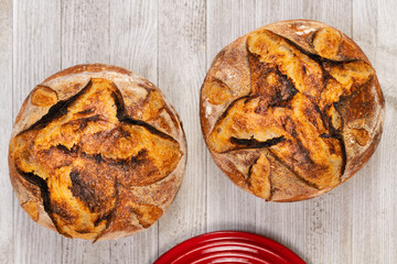 Traditional artisan bread with red baking pan, top view