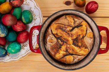 Traditional artisan bread in baking pan and Easter painted eggs