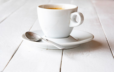 A cup of espresso on white painted boards.