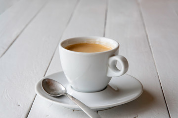 A cup of espresso on white painted boards.