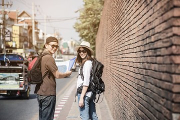 Asian backpack couple tourist holding city map crossing the road - travel people vacation lifestyle concept