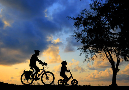 silhouette Father and son riding bicycle at sunset sky