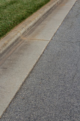 Obraz premium Long view of street, asphalt beside formed concrete curb and grass, vertical aspect