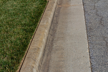 Nicely edged green grass alongside a formed concrete curb, horizontal aspect