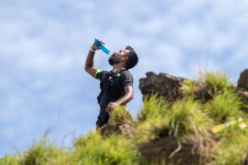 Trail runner drinking energy drink to energy in competition