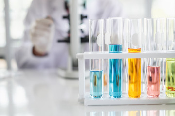 A scientist hands working in laboratory with test tube microscope and solutions.