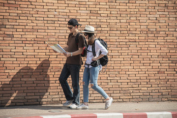 Asian backpack couple tourist holding city map crossing the road - travel people vacation lifestyle concept