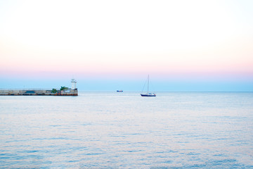 Sea sunset in summer in the evening with natural light Sea sunset, yachts in the sea near the lighthouse on a summer day in the background of beautiful colors in the sky 