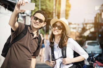 Asian backpack couple tourist holding city map crossing the road - travel people vacation lifestyle concept