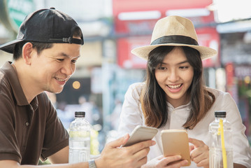 Asian couple enjoy traveling sitting at coffee shop - happy young people on vacation concept