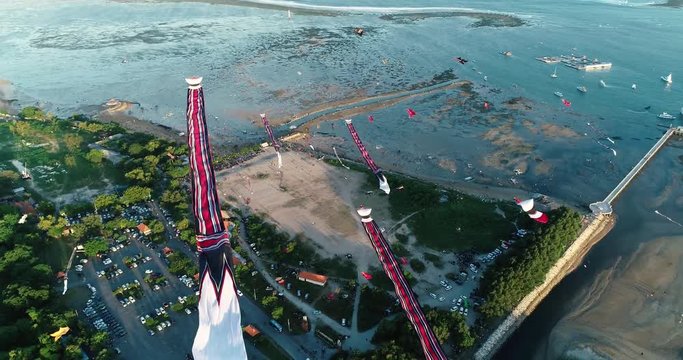 Aerial bird eye shot many traditional Balinese kites soaring in the air above seaside at sunset, Sanur, Bali, Indonesia. 4K