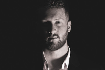 Obraz premium Handsome man with beard is watching you from the shadows
