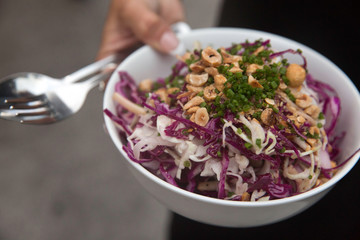 vegetable salad with waitress's hand and cutlery