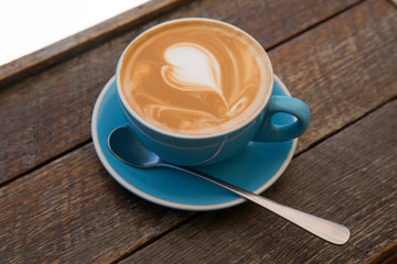 Capuccino with long spoon in Blue Cup and Saucer on wooden table 