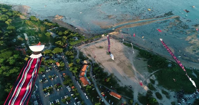 Aerial shot traditional Balinese kites soaring in the air above seaside at sunset, Sanur, Bali, Indonesia. 4K